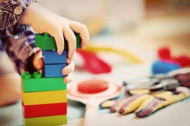 Symbolbild: Foto von Kinderhänden, die mit bunten Legosteinen spielen.