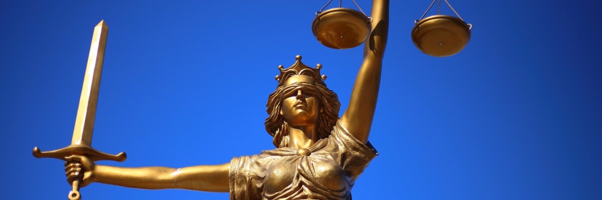 Symbolbild: Foto einer goldenen Justitia-Statue vor blauem Himmel